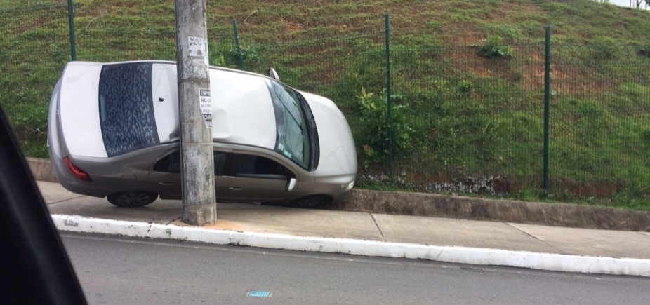Carro sobe em passeio e fica preso entre poste e colina